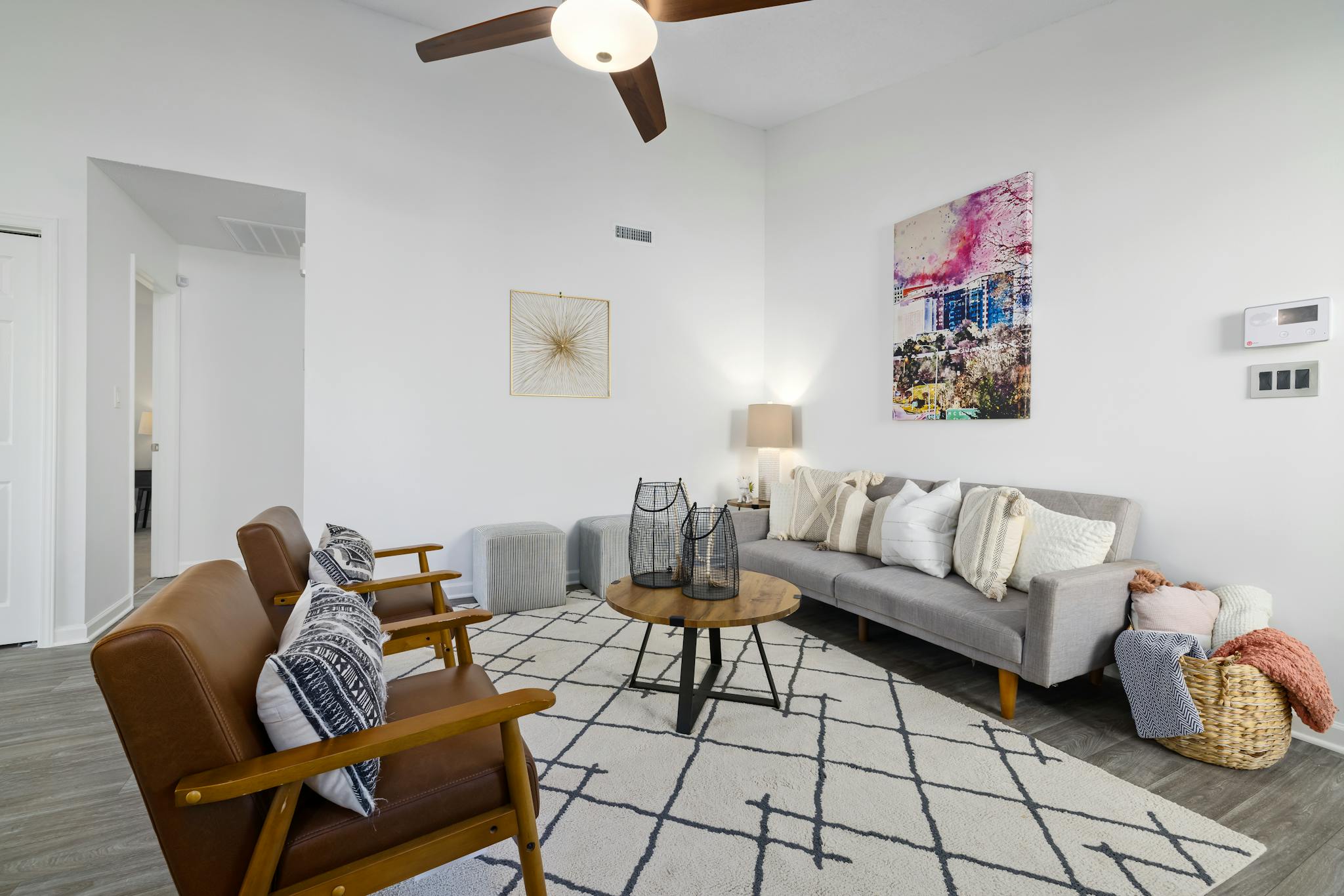Elegant and minimalistic living room with gray sofa, wooden armchairs, and stylish decor.