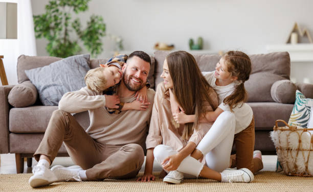 Happy family mother father and children at home on floor next to the sofa