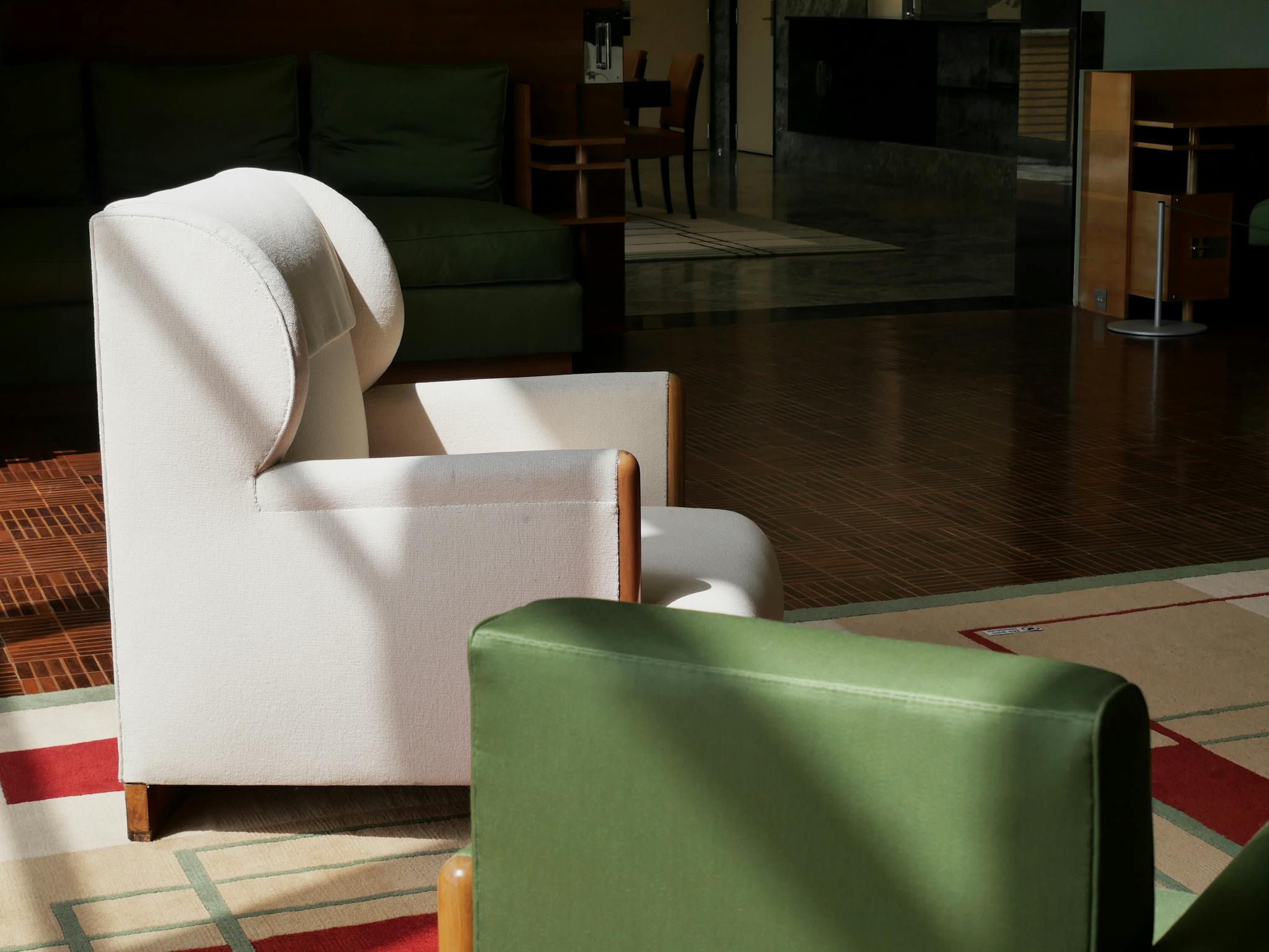 Modern armchairs in a sunlit interior with wooden flooring and green accents.
